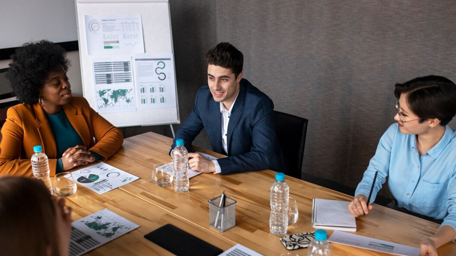 Business professionals in a meeting discussing audit and compliance strategy with Veritiq ARC software reports on the table